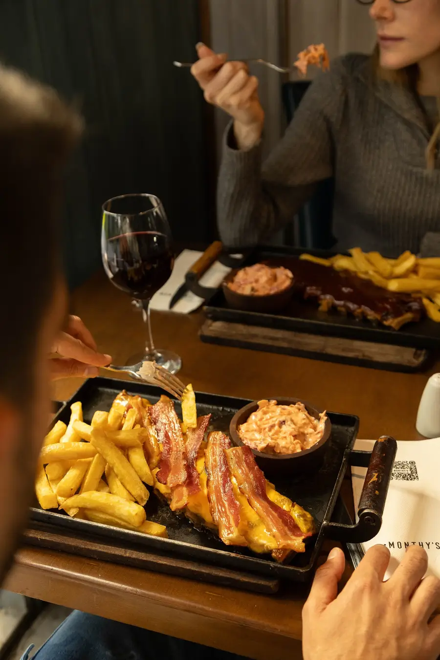 Ribs con papas fritas y vino tinto en una mesa de Monthy's Roadhouse, Pilar